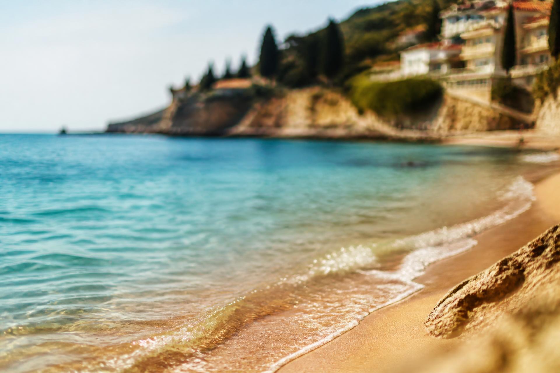 Turquoise Mediterranean sea meeting warm golden sand in soft summer light